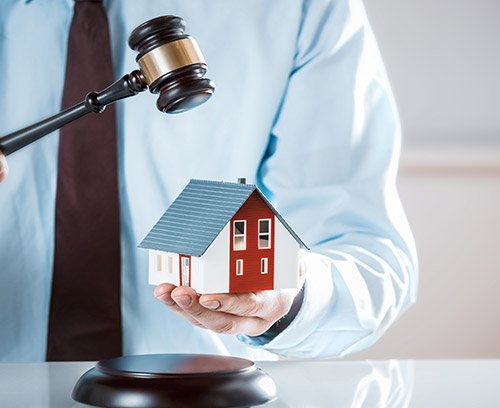 Maison miniature et marteau de juge sur un bureau
